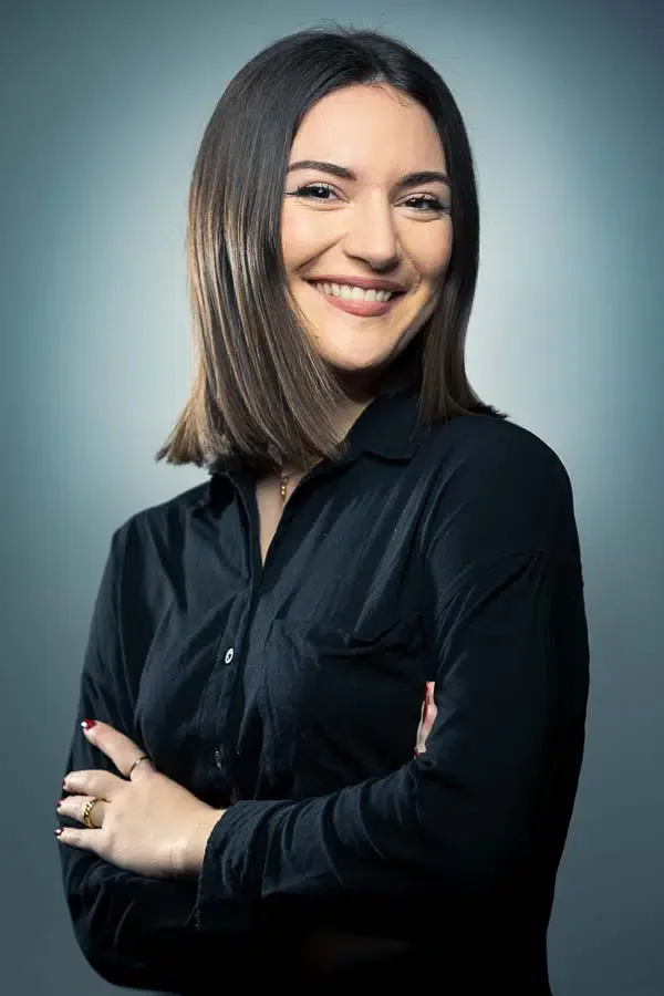 1. Jeune femme souriante avec cheveux bruns et veste noire, portrait professionnel.